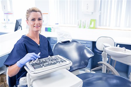 dentist tray - Dentist sitting with tray of tools smiling at camera at the dental clinic Stock Photo - Budget Royalty-Free & Subscription, Code: 400-07940825