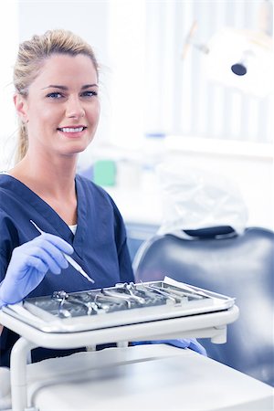 dentist tray - Dentist sitting with tray of tools smiling at camera at the dental clinic Stock Photo - Budget Royalty-Free & Subscription, Code: 400-07940826