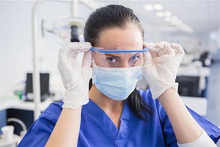 simsearch:400-07941454,k - Dentist with surgical mask putting on her safety glasses in dental clinic Stockbilder - Microstock & Abonnement, Bildnummer: 400-07941465