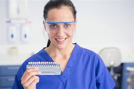 simsearch:400-07941465,k - Smiling dentist with safety glasses holding teeth whitening in dental clinic Stock Photo - Budget Royalty-Free & Subscription, Code: 400-07941462