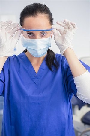 simsearch:400-07941465,k - Dentist with surgical mask putting on her safety glasses in dental clinic Stock Photo - Budget Royalty-Free & Subscription, Code: 400-07941463