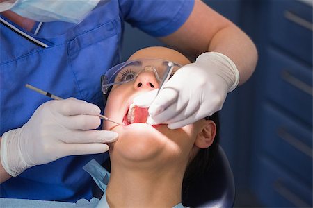 simsearch:400-07940798,k - Dentist examining a patient with angle mirror and sickle probe in dental clinic Foto de stock - Super Valor sin royalties y Suscripción, Código: 400-07941493