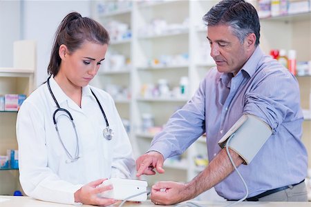 Young trainee taking blood pressure of his customer in the pharmacy Stock Photo - Budget Royalty-Free & Subscription, Code: 400-07941614