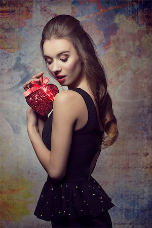 simsearch:400-07986693,k - Romantic, young, beautiful, bright, elegant girl in black dress is holding valentines present. Her makeup is perfect. Stock Photo - Budget Royalty-Free & Subscription, Code: 400-07955870