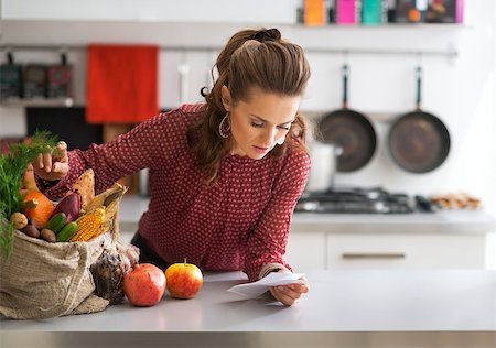 shopping bags in kitchen - Young housewife exploring checks after grocery shopping in kitchen Stock Photo - Budget Royalty-Free & Subscription, Code: 400-07955992