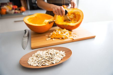 simsearch:400-07956836,k - Closeup on seeds and young housewife removing filling from pumpkin in background Foto de stock - Royalty-Free Super Valor e Assinatura, Número: 400-07956539