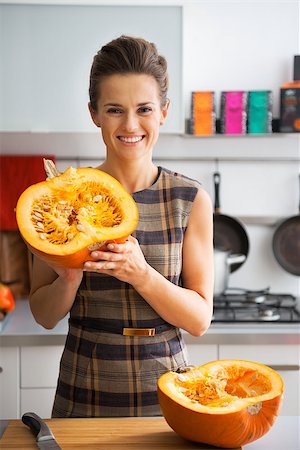 simsearch:400-07956018,k - Portrait of happy young housewife showing half of pumpkin Stockbilder - Microstock & Abonnement, Bildnummer: 400-07956532