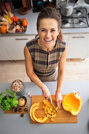 simsearch:400-07956836,k - Portrait of happy young housewife cutting pumpkin in kitchen Foto de stock - Royalty-Free Super Valor e Assinatura, Número: 400-07956562