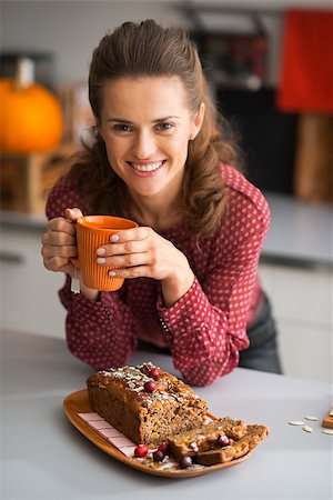 simsearch:400-07956836,k - Happy young housewife drinking tea with freshly baked pumpkin bread with seeds Foto de stock - Royalty-Free Super Valor e Assinatura, Número: 400-07956859