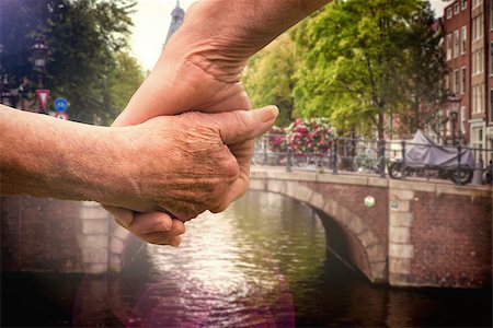 Elderly couple holding hands against canal in amsterdam Stock Photo - Budget Royalty-Free & Subscription, Code: 400-07957054