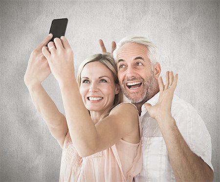 simsearch:400-07957430,k - Happy couple posing for a selfie against weathered surface Photographie de stock - Aubaine LD & Abonnement, Code: 400-07957394