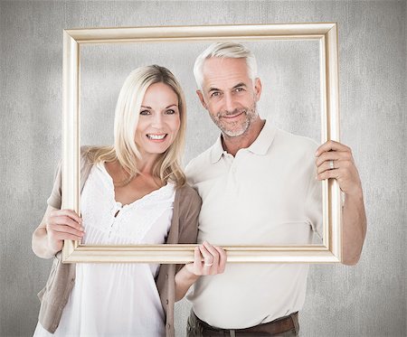 simsearch:400-07957339,k - Happy couple holding a picture frame against weathered surface Photographie de stock - Aubaine LD & Abonnement, Code: 400-07957405