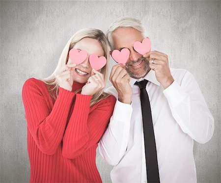 simsearch:400-07957430,k - Silly couple holding hearts over their eyes against weathered surface Photographie de stock - Aubaine LD & Abonnement, Code: 400-07957417