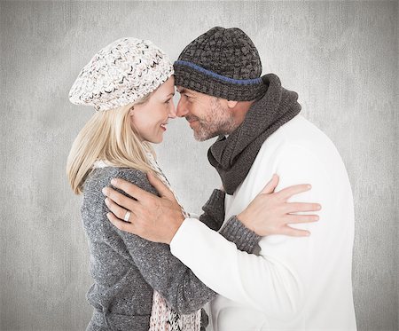 simsearch:400-07957339,k - Happy couple in winter fashion embracing against weathered surface Photographie de stock - Aubaine LD & Abonnement, Code: 400-07957427