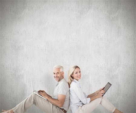 Happy couple sitting using laptop and tablet pc against weathered surface Photographie de stock - Aubaine LD & Abonnement, Code: 400-07957437