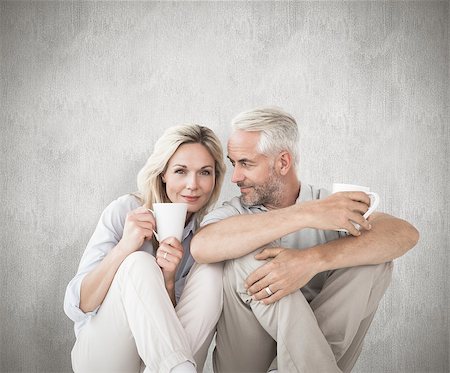 Happy couple sitting holding mugs against weathered surface Photographie de stock - Aubaine LD & Abonnement, Code: 400-07957438