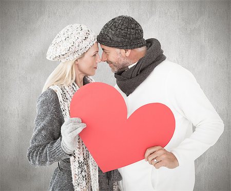 simsearch:400-07957430,k - Smiling couple in winter fashion posing with heart shape against weathered surface Photographie de stock - Aubaine LD & Abonnement, Code: 400-07957431