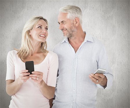 simsearch:400-07957460,k - Happy couple texting on their smartphones against weathered surface Foto de stock - Super Valor sin royalties y Suscripción, Código: 400-07957448