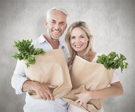 simsearch:400-07957430,k - Happy couple carrying paper grocery bags against weathered surface Photographie de stock - Aubaine LD & Abonnement, Code: 400-07957449