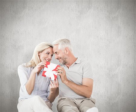 simsearch:400-07957627,k - Happy couple sitting and holding present against weathered surface Foto de stock - Super Valor sin royalties y Suscripción, Código: 400-07957440