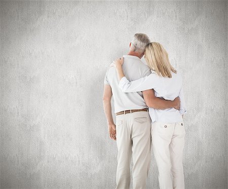 simsearch:400-07957430,k - Happy couple standing and looking against weathered surface Photographie de stock - Aubaine LD & Abonnement, Code: 400-07957443