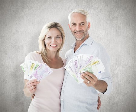 simsearch:400-07957339,k - Happy couple flashing their cash against weathered surface Photographie de stock - Aubaine LD & Abonnement, Code: 400-07957454