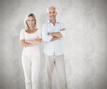 simsearch:400-07957339,k - Smiling couple standing with arms crossed against weathered surface Photographie de stock - Aubaine LD & Abonnement, Code: 400-07957457