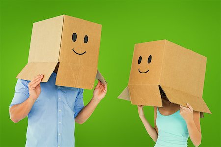 Couple wearing emoticon face boxes on their heads against green vignette Stock Photo - Budget Royalty-Free & Subscription, Code: 400-07957539