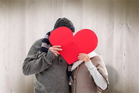 simsearch:400-07957430,k - Happy mature couple in winter clothes holding red heart against wooden planks Photographie de stock - Aubaine LD & Abonnement, Code: 400-07957634