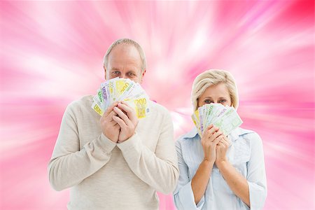 simsearch:400-07957006,k - Happy mature couple smiling at camera showing money against digitally generated girly heart design Stock Photo - Budget Royalty-Free & Subscription, Code: 400-07957816