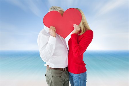 Couple embracing and holding heart over faces against beach scene Stock Photo - Budget Royalty-Free & Subscription, Code: 400-07957843