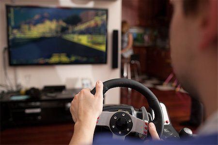 screen car - Back close-up shot of a man playing car racing video game using steering wheel Stock Photo - Budget Royalty-Free & Subscription, Code: 400-07953271