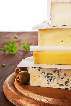emmentaler cheese - Various cheese pieces arranged on each other on brown wooden natural background with olives and parsley in background. Cheese background. Stock Photo - Budget Royalty-Free & Subscription, Code: 400-07974242