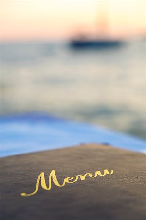 eating boat - A menu laid on a seafood restaurant table with a boat out of focus on the sea at sunset in the background Stock Photo - Budget Royalty-Free & Subscription, Code: 400-07975558