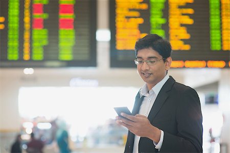 Asian Indian Business man checking on smartphone, doing online web check in at the airport . Stock Photo - Budget Royalty-Free & Subscription, Code: 400-07978334