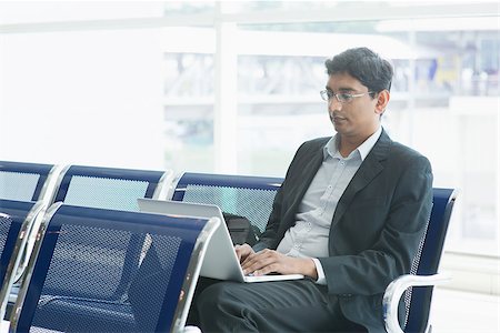 simsearch:400-07978342,k - Asian Indian business man waiting his flight at airport, sitting on chair and using laptop. Photographie de stock - Aubaine LD & Abonnement, Code: 400-07978338
