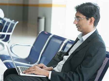 Asian Indian business man sitting on chair and using laptop while waiting his flight at airport. Stock Photo - Budget Royalty-Free & Subscription, Code: 400-07978339