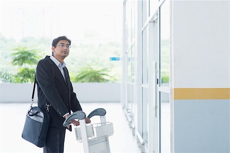 simsearch:400-07978342,k - Asian Indian businessman walking with airport trolley Photographie de stock - Aubaine LD & Abonnement, Code: 400-07978344