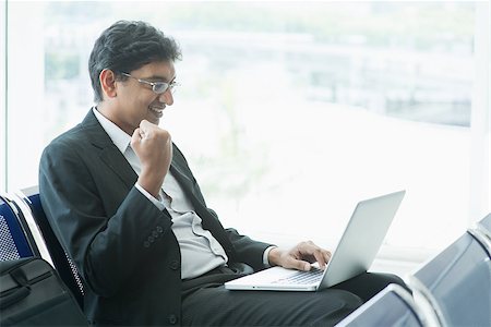 Asian Indian businessman sitting on chair and using laptop while waiting his flight at airport. Stock Photo - Budget Royalty-Free & Subscription, Code: 400-07978340