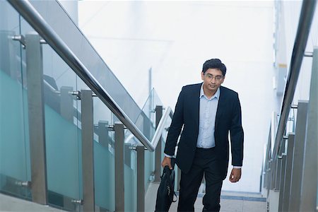 simsearch:400-07978342,k - Asian Indian corporate businessman in suit with briefcase ascending steps. Photographie de stock - Aubaine LD & Abonnement, Code: 400-07978343