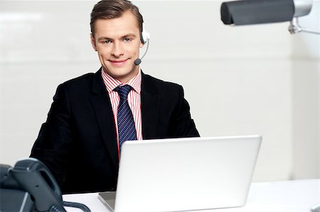 Smiling call centre executive posing with headsets. working on laptop Stock Photo - Budget Royalty-Free & Subscription, Code: 400-07987325