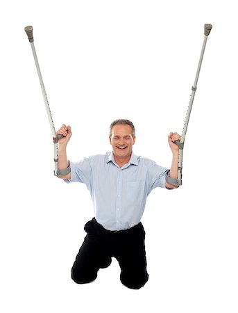 simsearch:400-07987656,k - Cheerful senior man holding crutches upwards seated on floor, studio shot Stock Photo - Budget Royalty-Free & Subscription, Code: 400-07987659