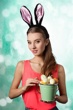 simsearch:400-06557487,k - Pretty, happy blonde woman with long hair and rabbit ears on the head. She is holding bucket of little Easter eggs. Stock Photo - Budget Royalty-Free & Subscription, Code: 400-07989923