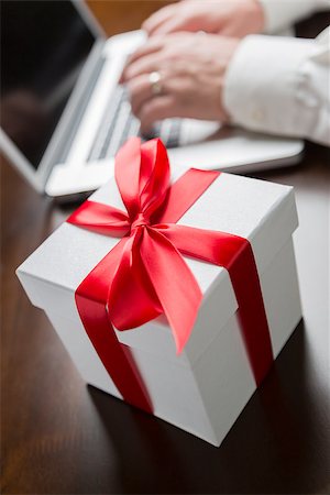 feverpitched (artist) - White Gift Box with Red Ribbon and Bow Near Man Typing on Laptop Computer. Foto de stock - Royalty-Free Super Valor e Assinatura, Número: 400-07982793