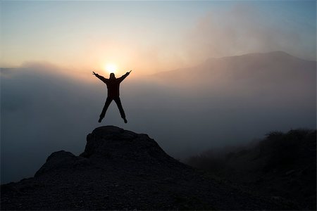 The woman jumps and  lifts her arms in victory. She contemplates beautiful sunset in mountains. Foto de stock - Super Valor sin royalties y Suscripción, Código: 400-07983386