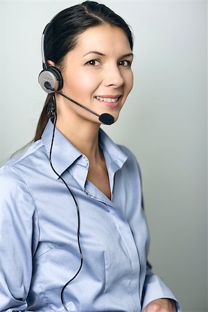 simsearch:400-04785322,k - Attractive female call center operator, client services assistant or telemarketer wearing a headset looking at the camera with a charming friendly smile, on grey with copy space Stock Photo - Budget Royalty-Free & Subscription, Code: 400-07994119