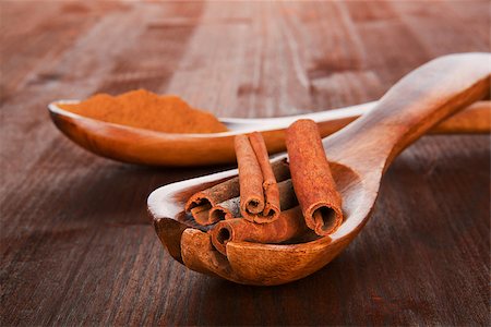 simsearch:400-04791848,k - Cinnamon sticks on spoon and cinnamon powder on wooden spoon in background. Brown natural culinary spice concept. Photographie de stock - Aubaine LD & Abonnement, Code: 400-07994440