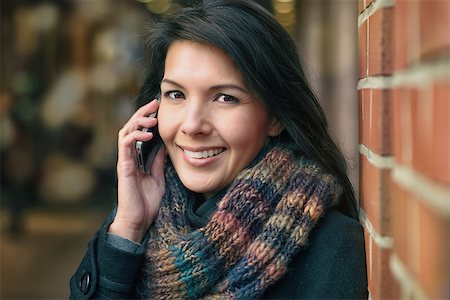 Smiling Young Woman in Autumn Fashion Talking on Phone While leaning against a red brick pillar Stock Photo - Budget Royalty-Free & Subscription, Code: 400-07995536