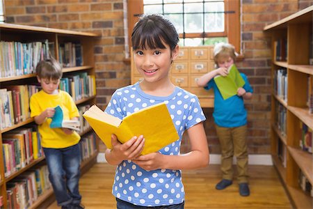 simsearch:400-07991158,k - Cute pupil smiling at camera in library at elementary school Stock Photo - Budget Royalty-Free & Subscription, Code: 400-07991104