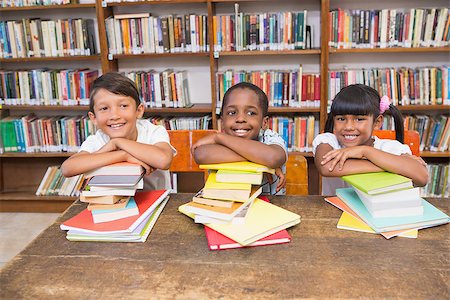 simsearch:400-07991158,k - Cute pupils smiling at camera at the library at elementary school Stock Photo - Budget Royalty-Free & Subscription, Code: 400-07991143